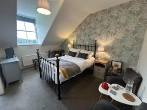 a bedroom with a bed and a couch and chairs at Archway Guest House in Windermere