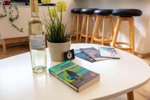 una mesa blanca con una botella de vino y un libro en L'Auguière Est, maisonnette sans vis-à-vis et au calme avec vue sur les vignes en Hyères