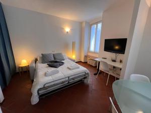 een slaapkamer met een bed, een bureau en een televisie bij Sandro's Home 2 in Bergamo