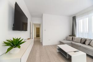a white living room with a couch and a tv at Nubia Apartment in Braşov