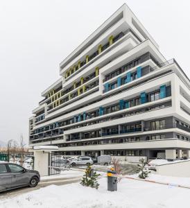 a large white building with cars parked in front of it at Nubia Apartment in Braşov