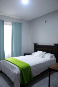 Un dormitorio con una cama con una manta verde. en Cortezas House, en Aguas Zarcas