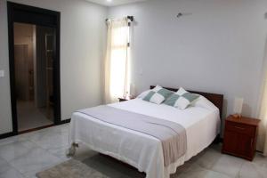 a bedroom with a large white bed and a window at Cortezas House in Aguas Zarcas