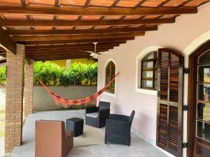una casa con un patio con sillas y una hamaca en Casa com Piscina Exclusiva - Condomínio em frente ao Mar - Portaria 24h, en Caraguatatuba