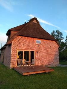 una casa con tetto di paglia e terrazza in legno di Erholung auf dem Land zwischen Ostsee und Schlei a Stoltebüll