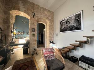 a living room with a stone wall with a chair and a piano at נרקיס NARKIS in Jerusalem