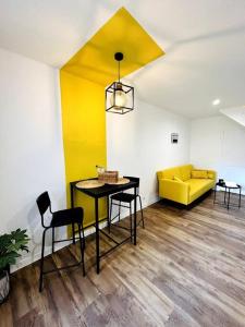 sala de estar con mesa y sofá amarillo en La Chaleureuse, en Vals-les-Bains