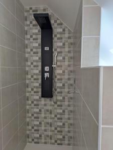 a shower with a black item on a tile wall at Chambre d hôte Beaumont pied de bœuf in Beaumont-Pied-de-Boeuf