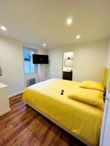 1 dormitorio con cama amarilla y TV en La Chaleureuse, en Vals-les-Bains