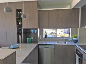 a kitchen with wooden cabinets and a sink and a window at Salt at Oceanside in Kawana Waters