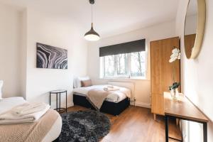 a bedroom with two beds and a table and a mirror at Onyx - 3 Bedroom House in Southampton