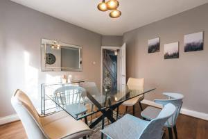 uma sala de jantar com uma mesa de vidro e cadeiras em Onyx - 3 Bedroom House em Southampton