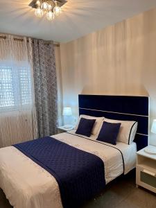a bedroom with a large bed with a blue headboard at Apartamentos Dalia in Vecindario +69 photos