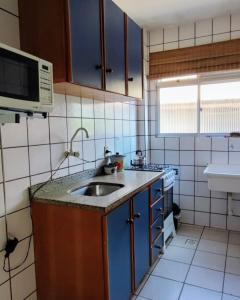 una pequeña cocina con fregadero y microondas en Canasvieiras Apto 150m da praia churrasqueira e garagem, en Florianópolis