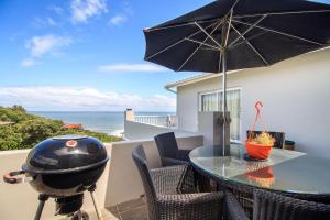 un patio con barbecue, tavolo e ombrellone di Cherry on Top a Morgan's Bay