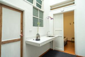 baño blanco con lavabo y ventana en Happina Suites, en Pasto