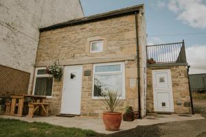 a brick building with white doors and a potted plant at Whiteside Granary in Haltwhistle