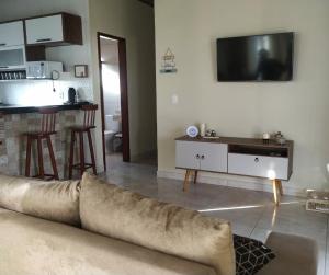 a living room with a couch and a flat screen tv at Chalé Pôr do Sol in Bananeiras