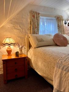 een slaapkamer met een bed en een tafel met een lamp bij Tosses Cottage - Secluded cottage with hot tub in Newry