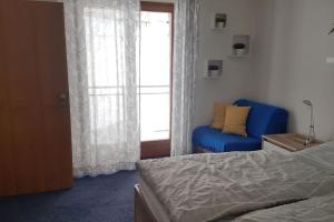a bedroom with a bed and a blue chair and a window at Apartment, 2 bedrooms, kitchen+2 bathrooms in Mitterfirmiansreut