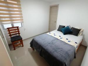 1 dormitorio con 1 cama, 1 silla y 1 ventana en Departamento por estrenar a 150 metros de la playa, en Tonsupa