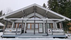 ein kleines weißes Haus mit einer Veranda im Schnee in der Unterkunft Villa Aurora, Himos in Jämsä
