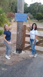 two women standing next to a wooden pole with a sign at VILA ACONCHEGO AZUL- casa 1 in Aracê +39 photos