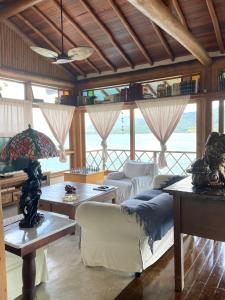 un soggiorno con divano, tavoli e finestre di Magnífica Costeira a Ilhabela