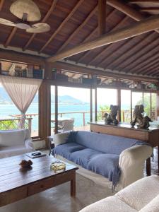 un soggiorno con un divano blu e un tavolo di Magnífica Costeira a Ilhabela