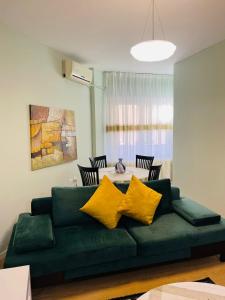 uma sala de estar com um sofá verde com almofadas amarelas em New Apartment in Center of Tirana em Tirana