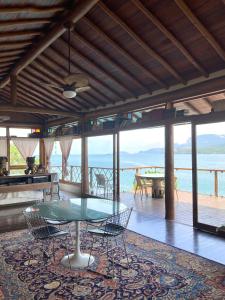 a table and chairs in a room with a view of the ocean at Magnífica Costeira in Ilhabela