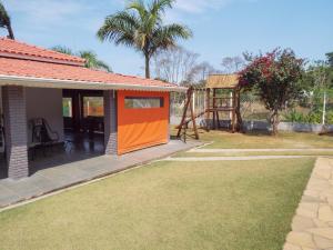 an orange door on a house with a yard at Chácara Recanto da Paz in Pinhalzinho