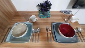 a wooden table with two plates and forks and spoons at Cozy 1Br with Netflix & Balcony Pool View Condo in Manila