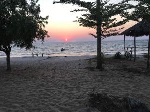 um pôr do sol na praia com pessoas na água em VILLA 3 DAUPHINS A 80 M DE LA PLAGE em Mahajanga
