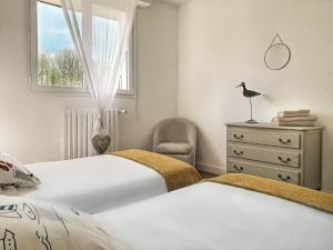 2 camas en un dormitorio con ventana y silla en Gîte ti Goudoul bébés enfants friendly en Moëlan-sur-Mer
