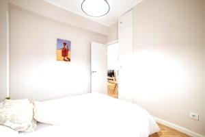 a white bedroom with a bed and a lamp at MyHouseSpain - Superb apartment close to Madrid City Center in Madrid