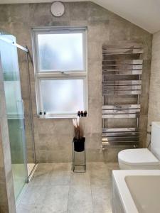 La salle de bains est pourvue d'une douche, de toilettes et d'une fenêtre. dans l'établissement Private House With FREE Parking, à Londres