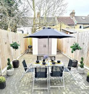 a table and chairs with an umbrella on a patio at Private House With FREE Parking in London