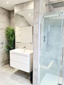 La salle de bains est pourvue d'un lavabo blanc et d'une douche. dans l'établissement Private House With FREE Parking, à Londres