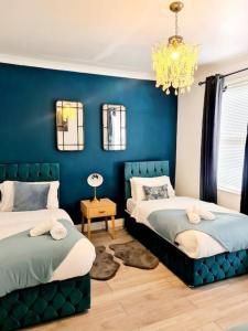 a blue bedroom with two beds and a chandelier at Private House With FREE Parking in London