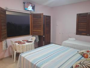 a bedroom with two beds and a table and a tv at Pousada Chalés do Castelo in Icapuí