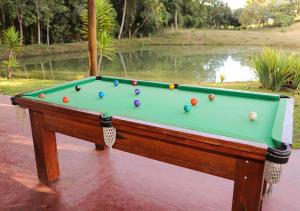 a pool table with balls on it next to a pond at Pousada Doce Recanto in Soledade de Minas