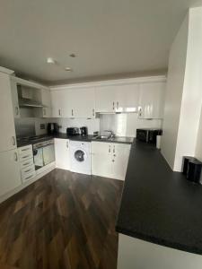 a kitchen with white cabinets and a wooden floor at Modern 2-Bed Apartment in Glasgow SECC/HYDRO in Glasgow