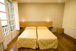 two beds in a room with two windows at Roquefer Bilbao Central Rooms in Bilbao