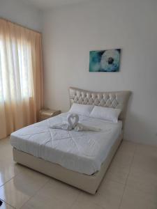 um quarto com uma cama branca com um laço em Cozy 3 Bedrooms Apartment Langkawi em Kuah