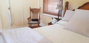 a bedroom with a bed and a chair and a window at Gum Paddock Country Cottage in Broken Hill