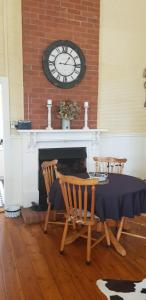 comedor con mesa y reloj sobre una chimenea en Gum Paddock Country Cottage, en Broken Hill