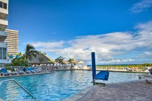 a swimming pool at a resort with blue chairs and the ocean at Luxe Waterfront Ft Lauderdale Condo with Beach, Pool apts in Fort Lauderdale