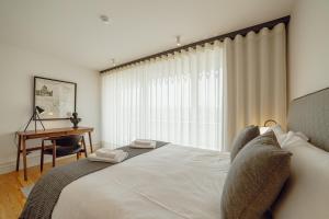 Schlafzimmer mit einem Bett, einem Schreibtisch und einem Fenster in der Unterkunft Downtown Penthouse With River View by Vacationy in Porto
