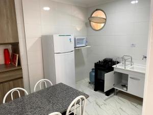 uma pequena cozinha com um frigorífico branco e uma mesa em Studio na praia da ENSEADA no Guarujá